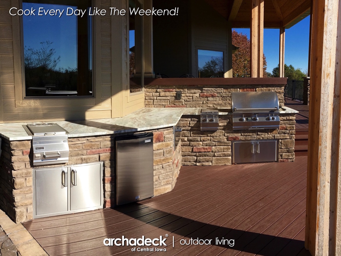 A patio with a grill and a stone wall